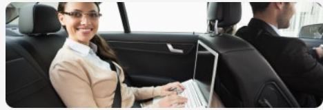 Passenger working on a laptop in the back of a car