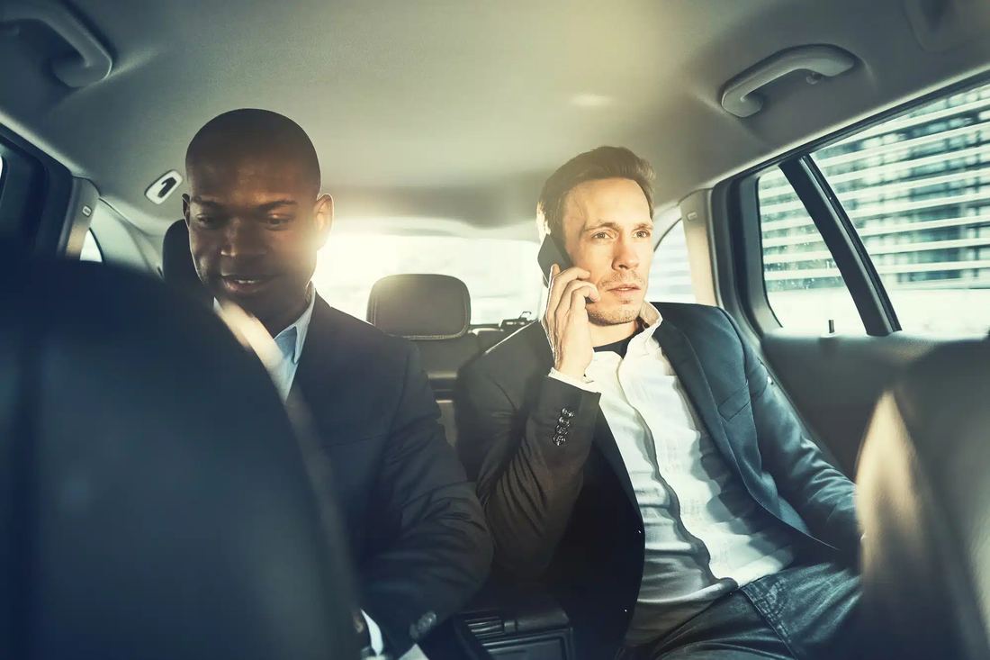 Two passengers talking in the back of a chauffeured car